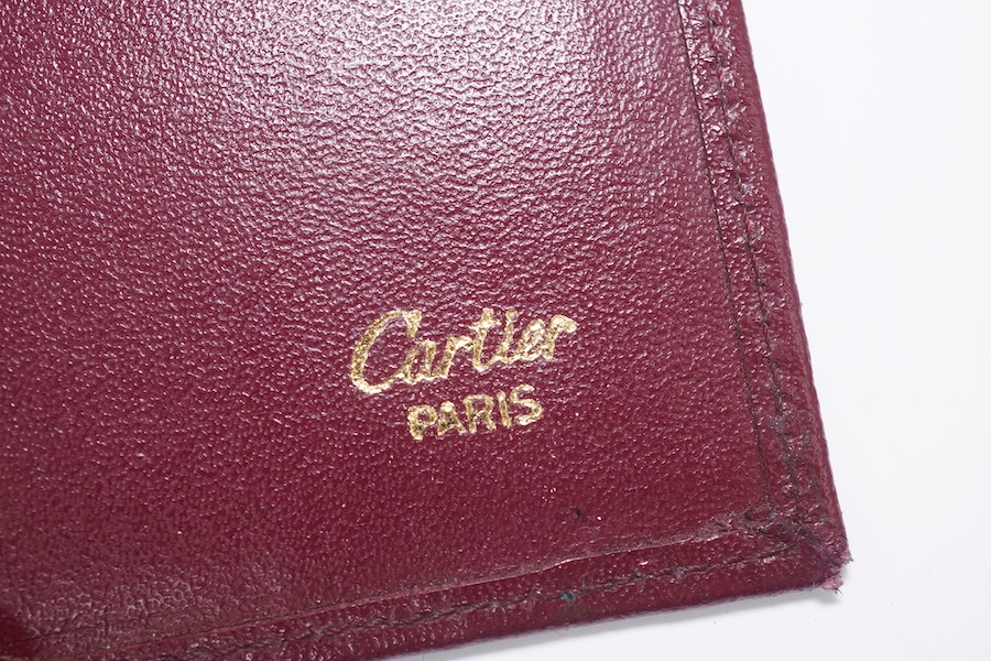 An assortment of Must de Cartier bordeaux leather accessories